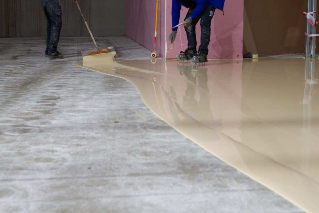 worker applying resistant epoxy resin to a floor